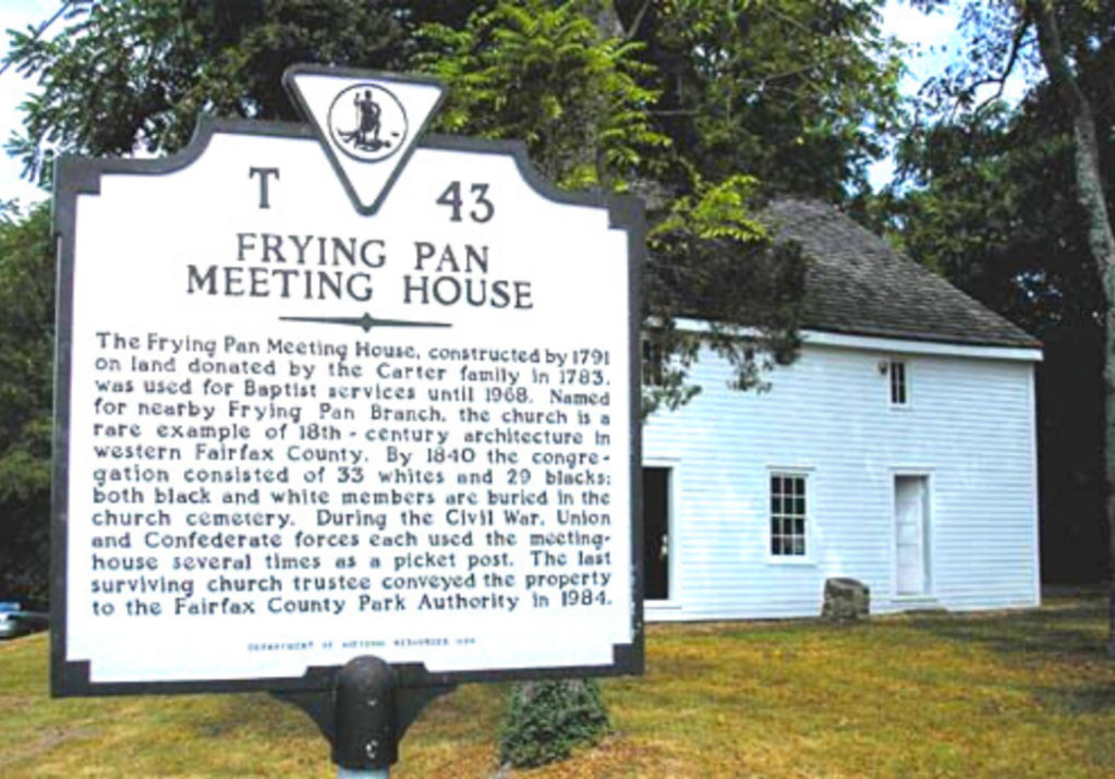 a marker for the Frying Pan Meeting House in front of the meeting house. Text reads: The Frying Pan Meeting House, constructed by 1971 on land donated by the Carter family in 1783 was used for Baptist services until 1968.