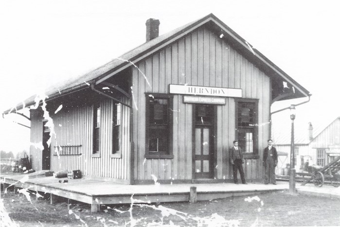 a black and white, worn photo of the Herndon train station